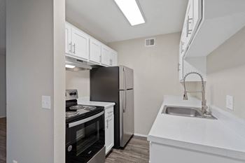 Kitchen with white cabinets and black appliances and a stainless steel refrigerator